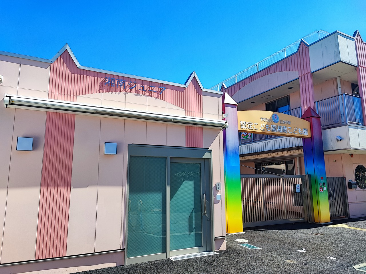 湘南ジュニアの建物の外観。淡いピンクの外壁と正面の入口
